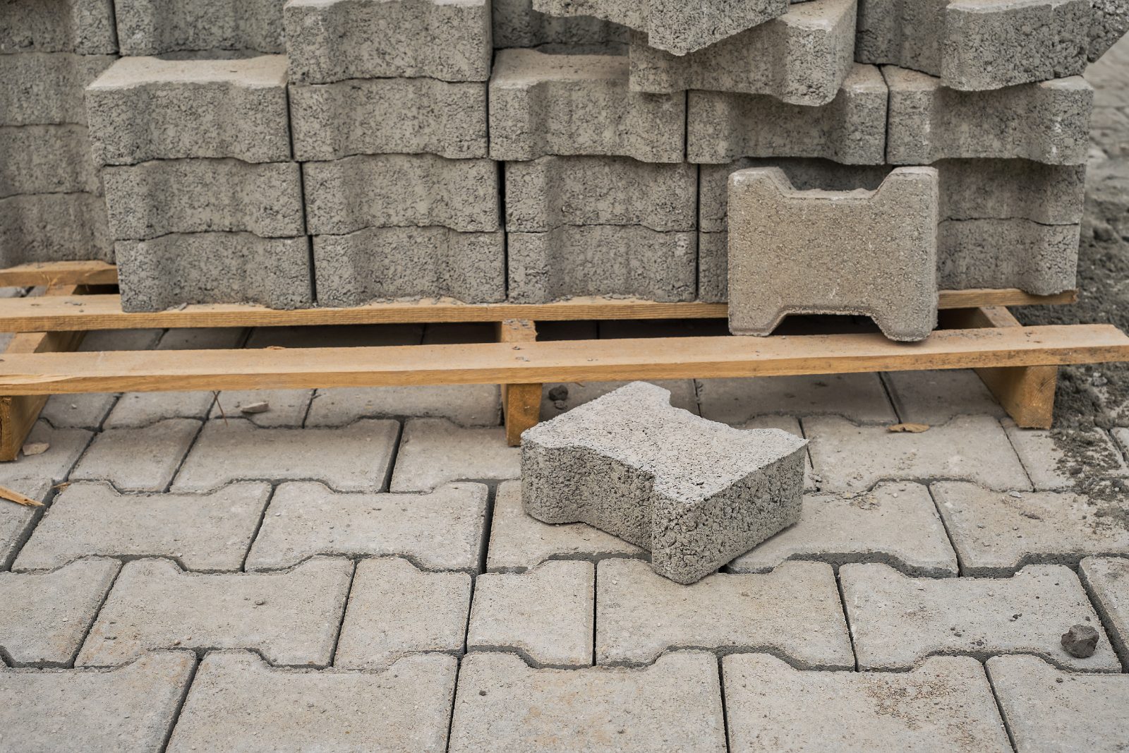 Pozycjonowanie brukarstwa - betonowa kostka brukowa na palecie obok świeżo ułożonej nawierzchni