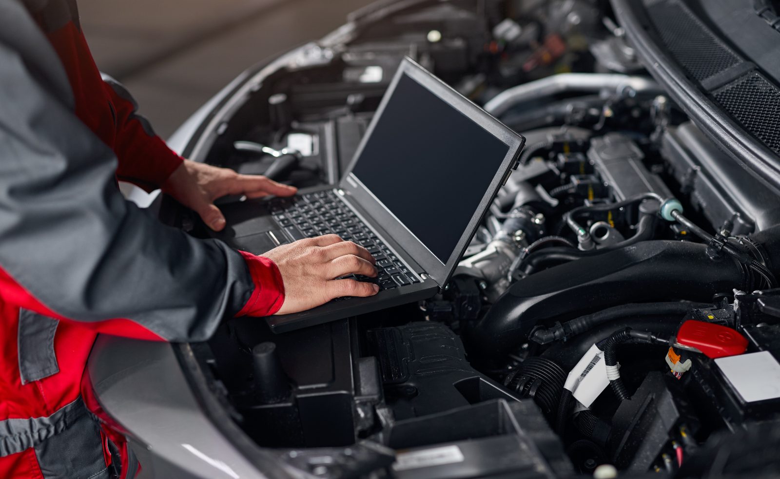 Mechanik z laptopem podłączonym do sterownika silnika podczas chiptuningu