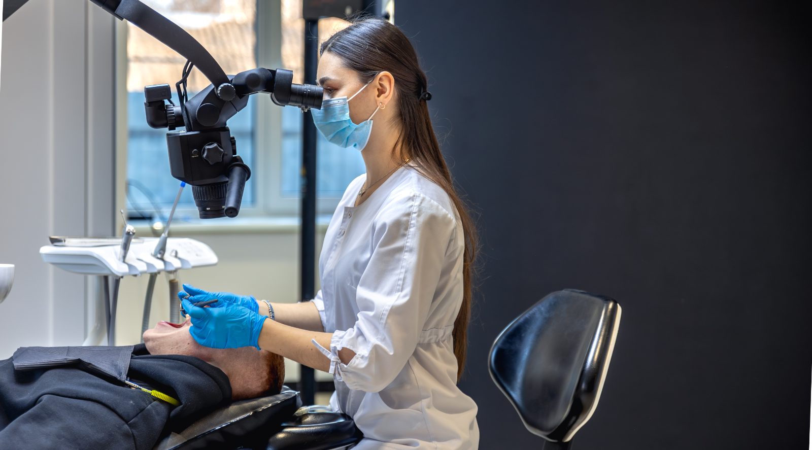 Pozycjonowanie endodonty - stomatolog leczy ząb pacjenta pod mikroskopem stomatologicznym