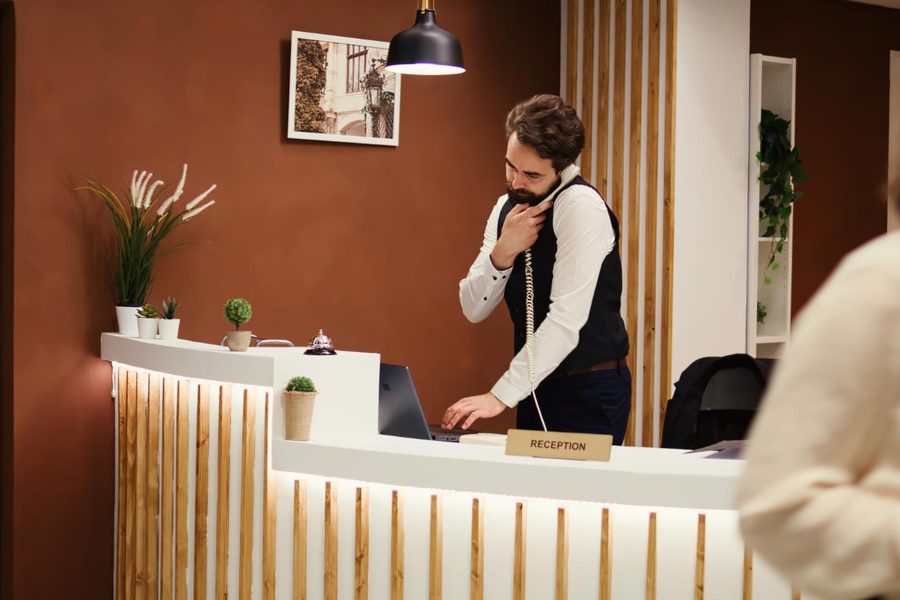 Pozycjonowanie hoteli — recepcjonista przy ladzie recepcji hotelowej