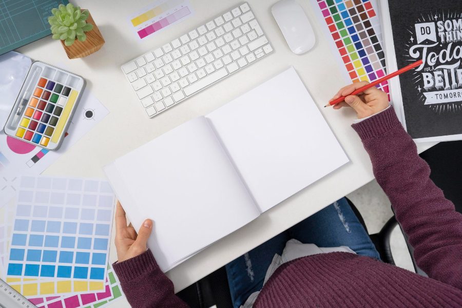 Pozycjonowanie firm od materiałów reklamowych - projekty ulotek i katalogów na biurku grafika