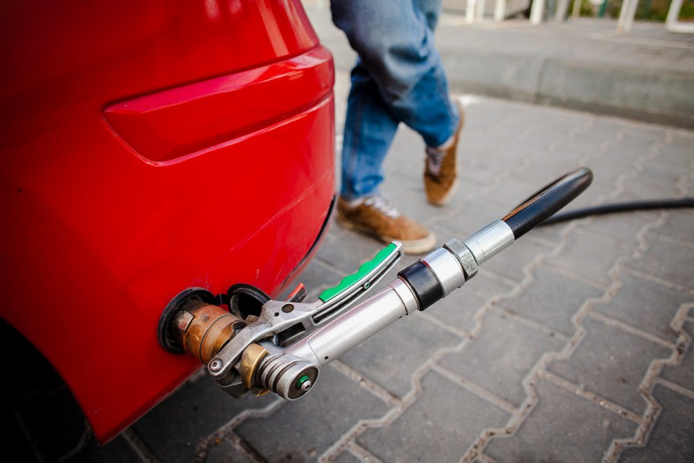 Pozycjonowanie montażu LPG - pistolet dystrybutora LPG wpięty w zawór tankowania w zderzaku czerwonego auta