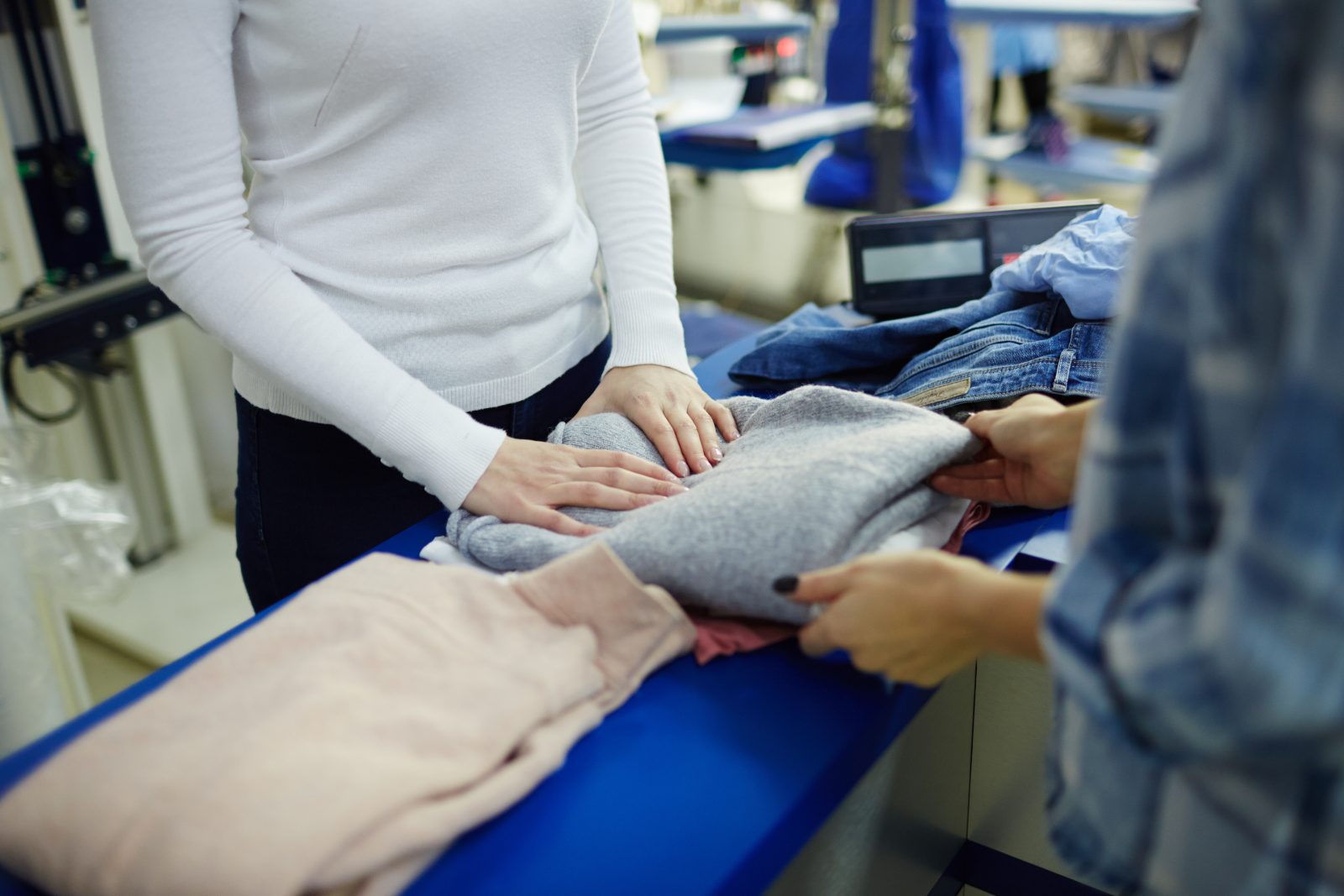 Pozycjonowanie pralni chemicznej - pracownica pralni przy ladzie oddaje klientowi złożony sweter