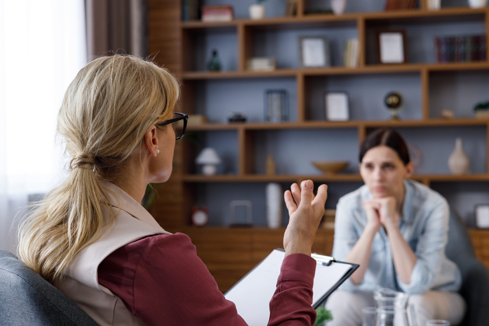 Pozycjonowanie psychoterapeuty - terapeutka z notatnikiem rozmawia z pacjentką w gabinecie psychoterapii