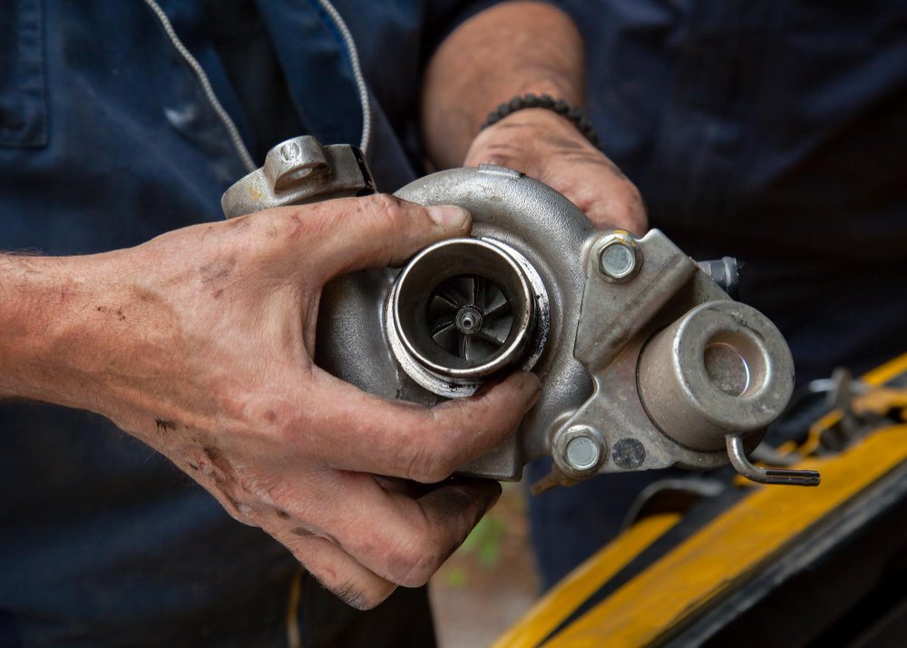 Pozycjonowanie regeneracji turbin - dłonie mechanika trzymają turbosprężarkę z widocznym wirnikiem