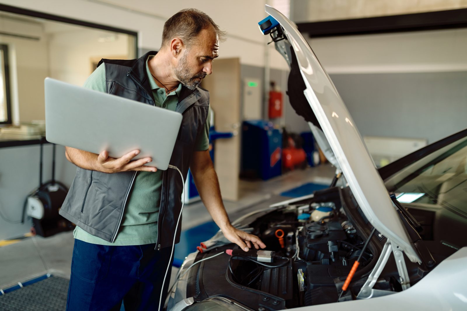 Technik z laptopem podczas diagnostyki samochodu w serwisie