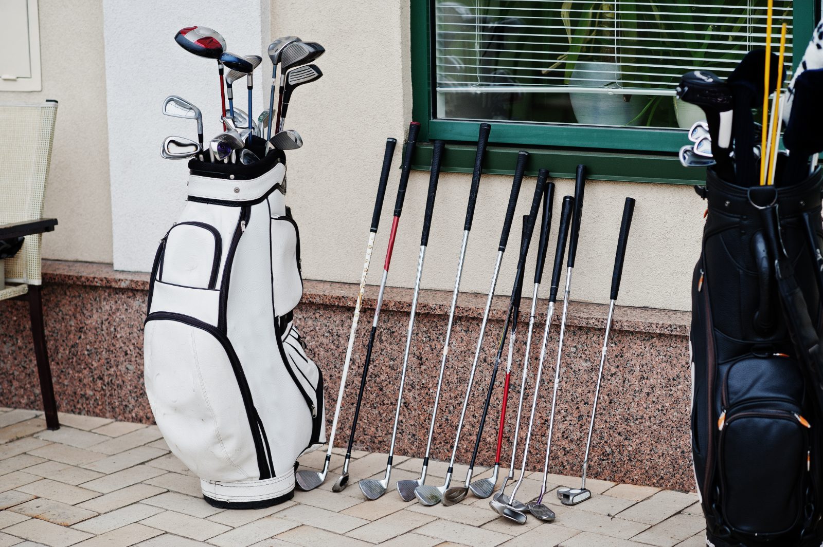 Torby golfowe i zestaw kijow ustawione przy budynku klubowym