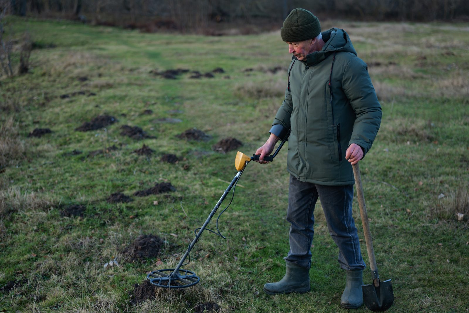 Poszukiwacz z wykrywaczem metali na polu o poranku