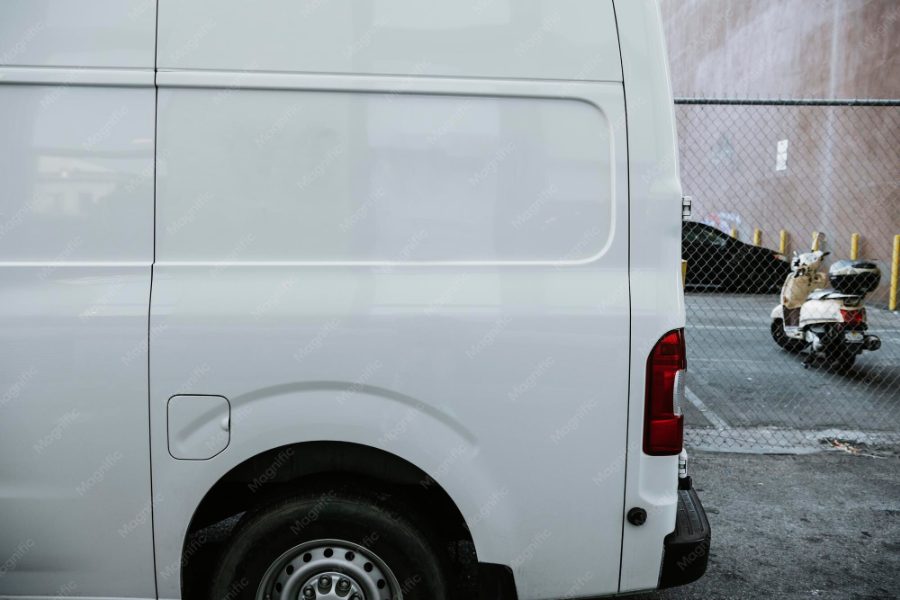 Pozycjonowanie taxi bagażowego — biały bus dostawczy zaparkowany przy ulicy podczas przewozu bagażu