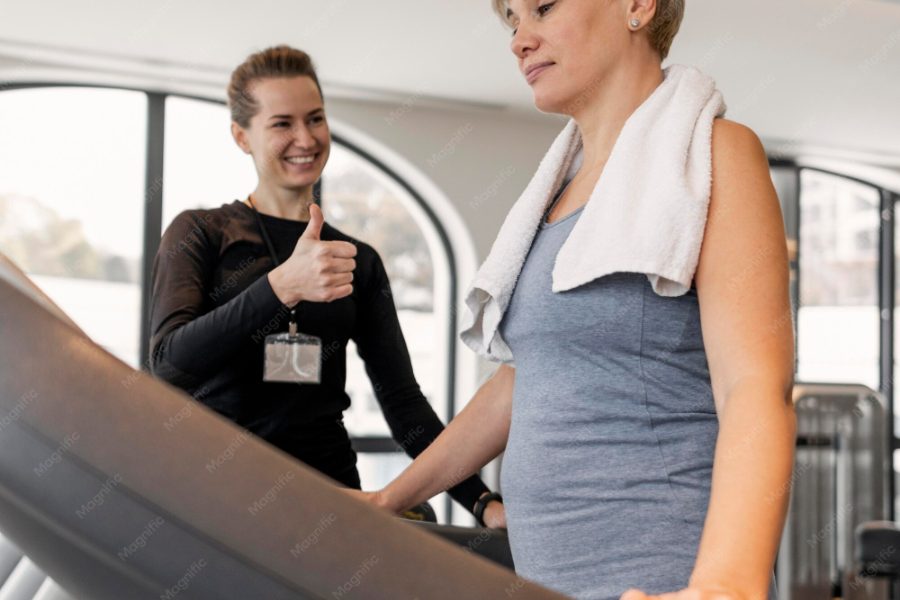 Pozycjonowanie trenera personalnego — trenerka prowadząca trening z klientką na siłowni