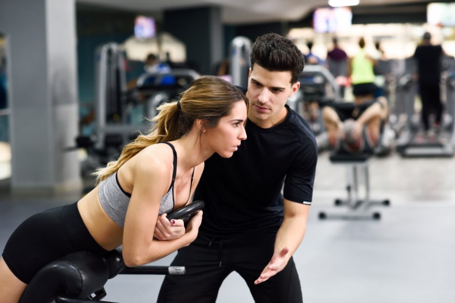 Pozycjonowanie trenera personalnego - trenerka prowadząca trening z klientką na siłowni